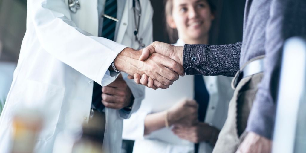 Handshake between doctor and businessperson. 