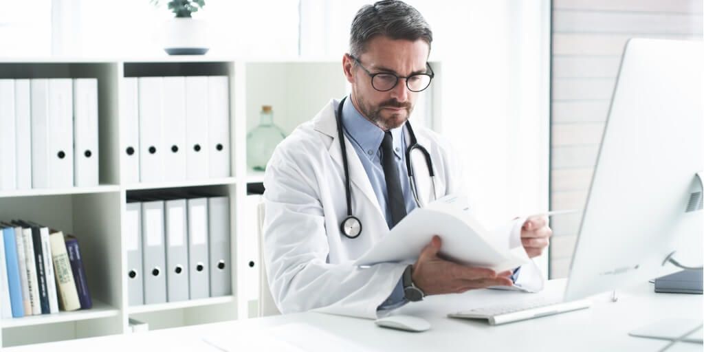 Male physician reading notes on a patient