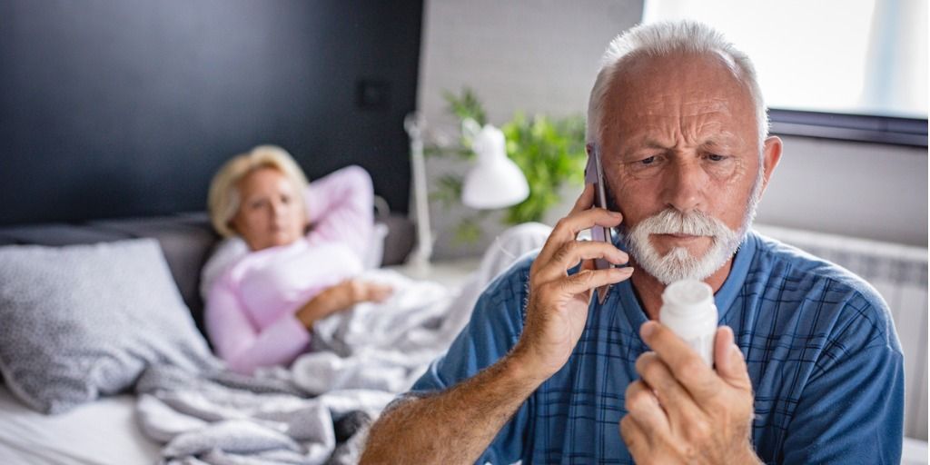 Man on the phone with his doctor while looking at a prescription bottle. 