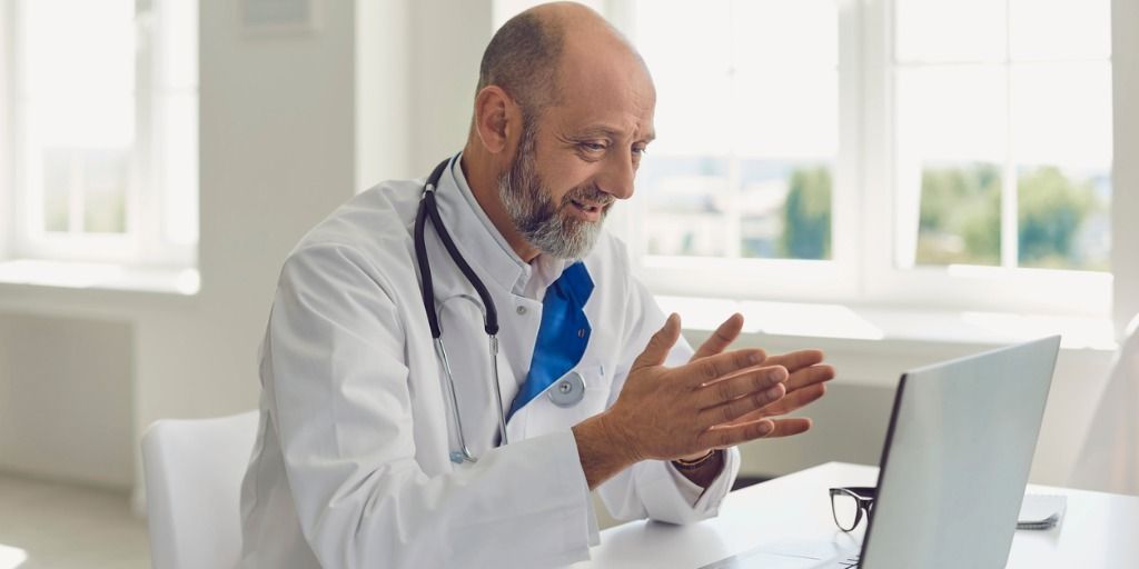 Doctor talking to patient through laptop video conference. 