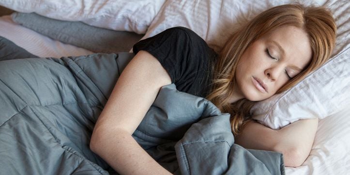 Woman sleeping under a weighted blanket