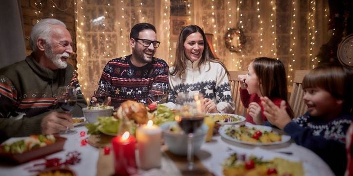 Family laughing around a dinner table while enjoying a holiday meal