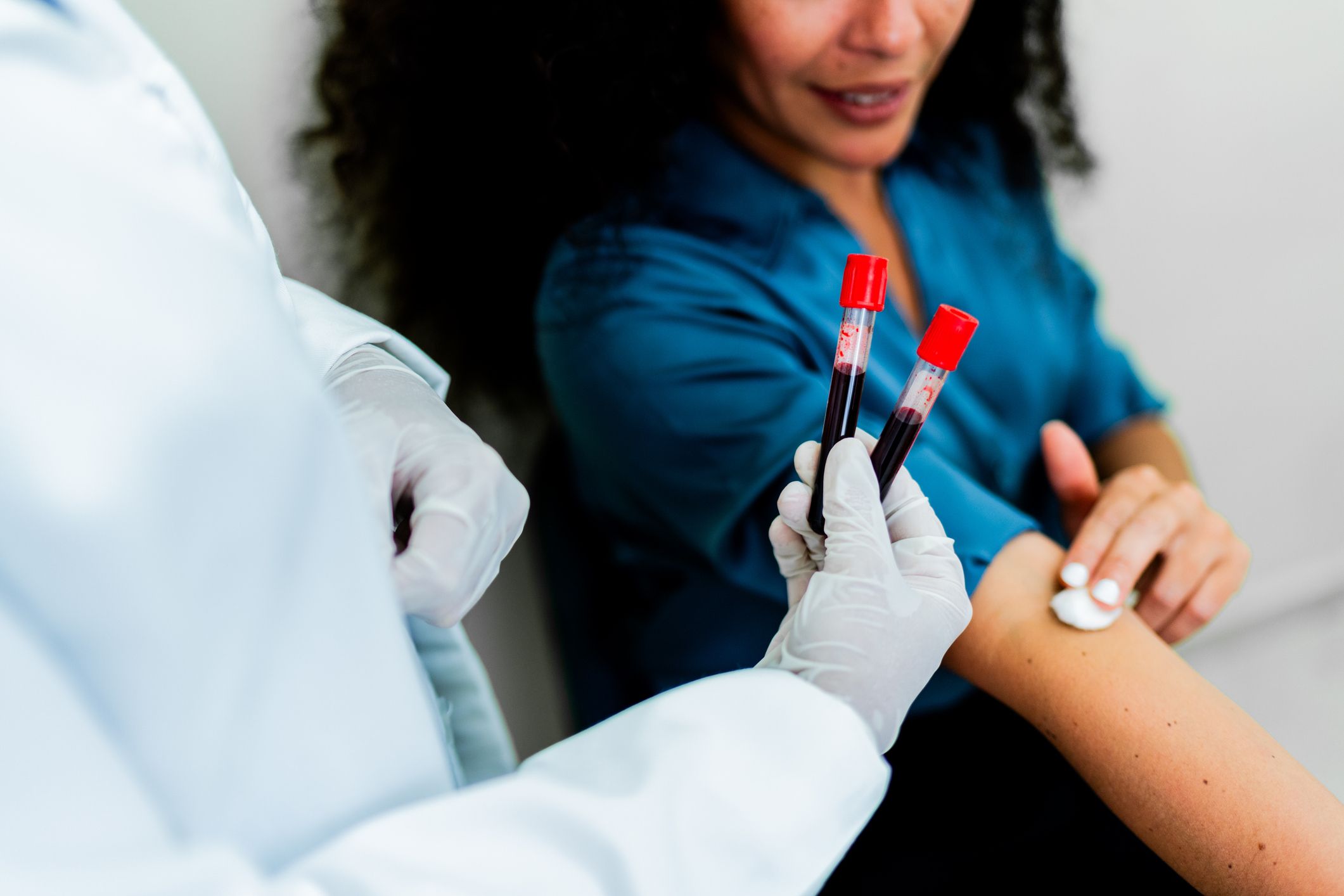 Doctor taking blood vials from patient.