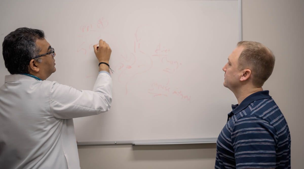 Dr. Sarma teaching a patient about holistic medicine by drawing, one of his common practices.