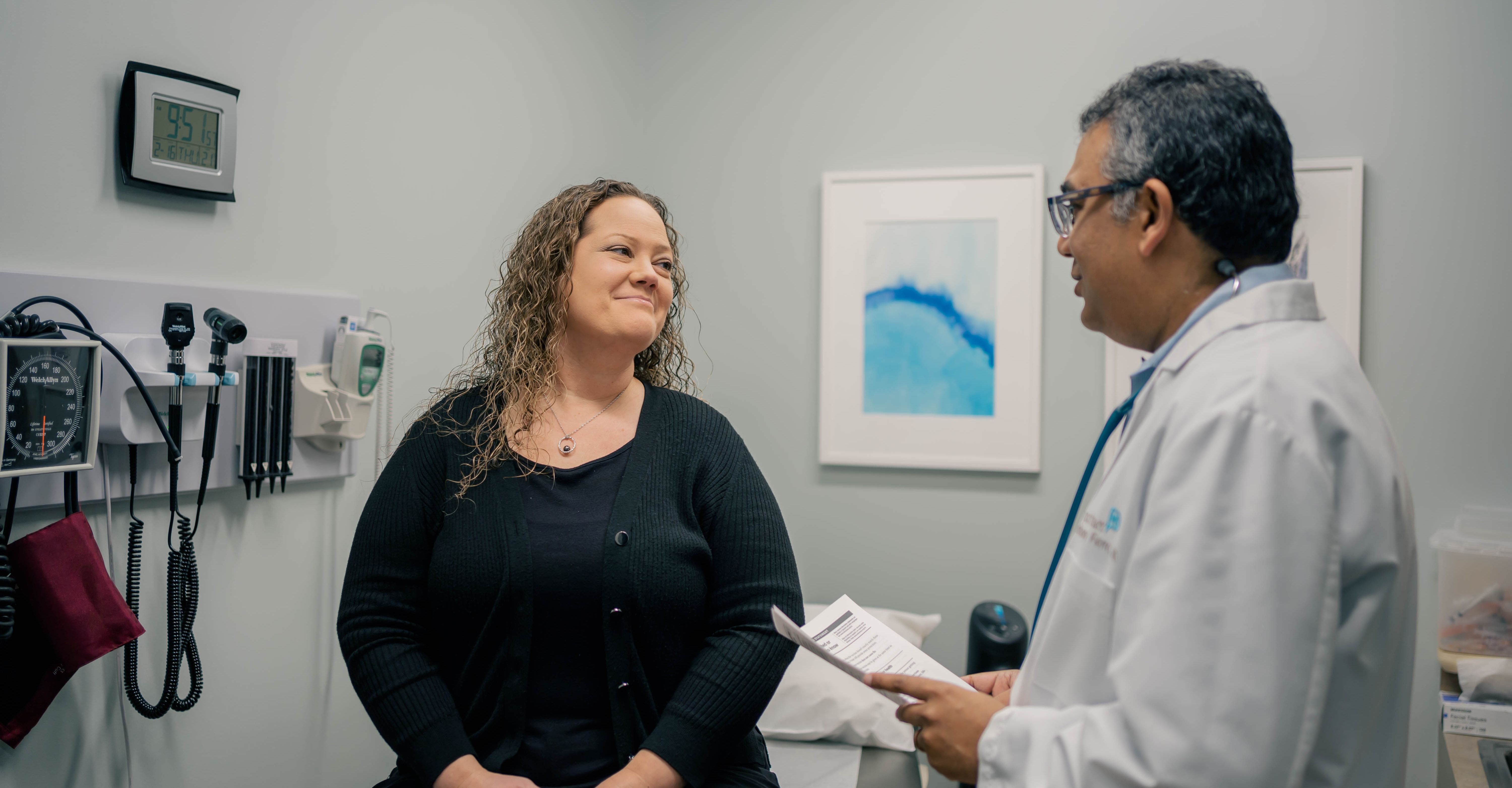 Concierge doctor talking with a female patient in an exam room