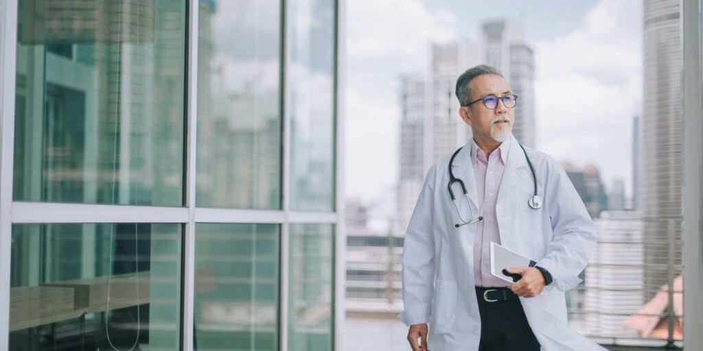 Male physician outside a hospital.