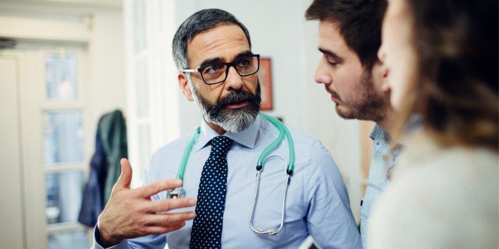 Male physician talking with two patients