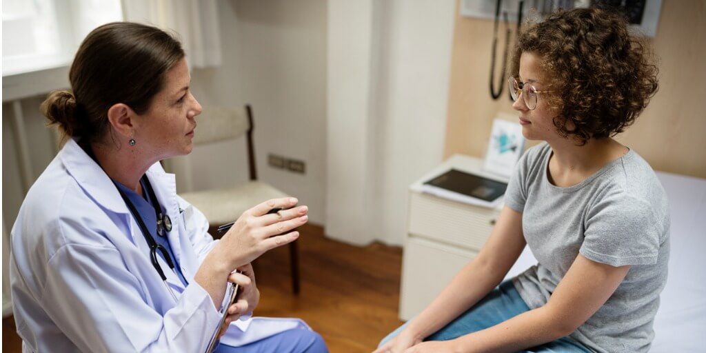 Female concierge doctor in exam room talking with young child