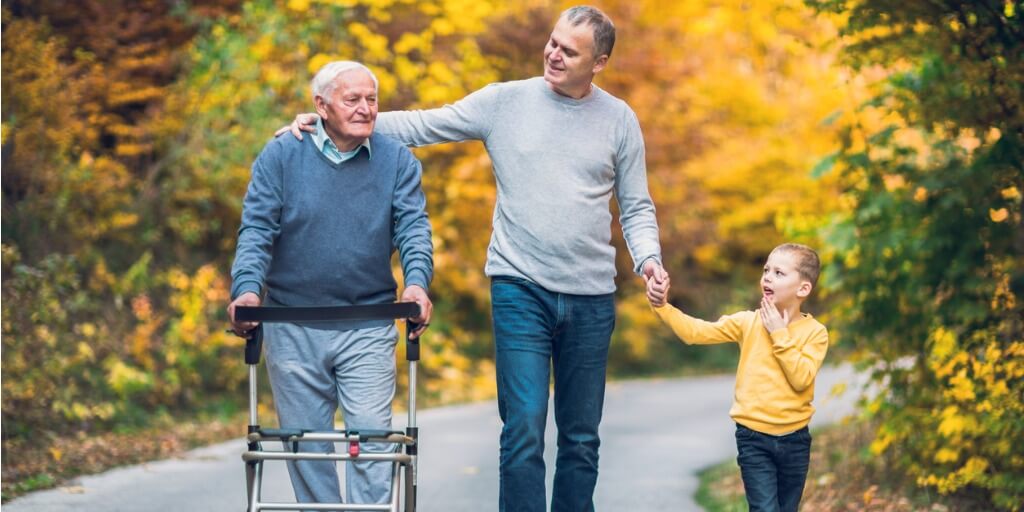 Elderly father, adult son, and his son walking in park