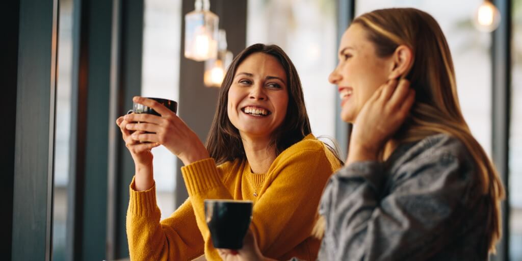 Two young, female friends talking about new primary care physicians over coffee. 