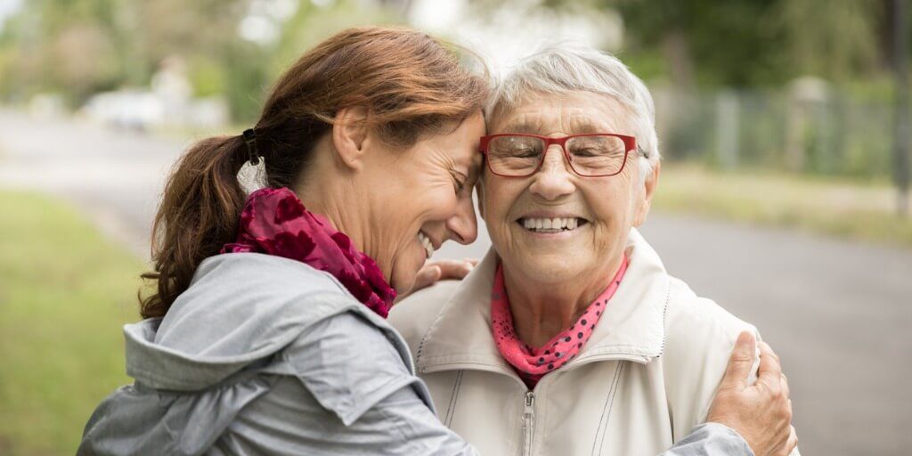 Daughter happy and hugging her elderly mother