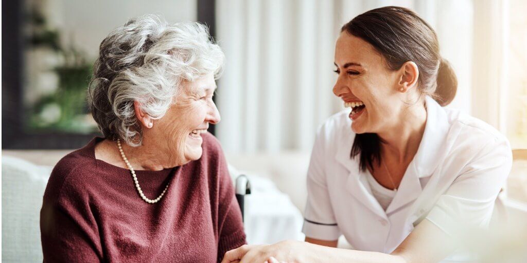 Elderly woman laughing with healthcare professional