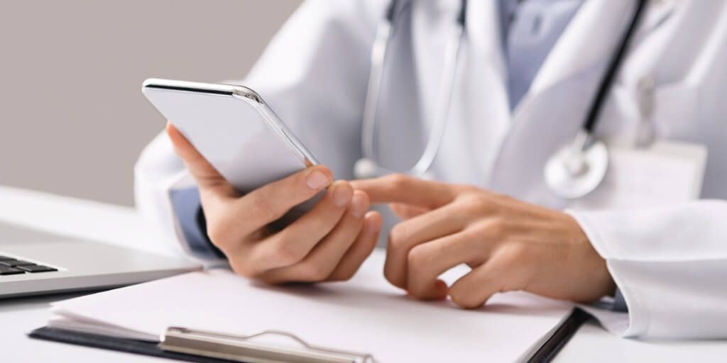 Doctor holding smartphone while talking to patient. 