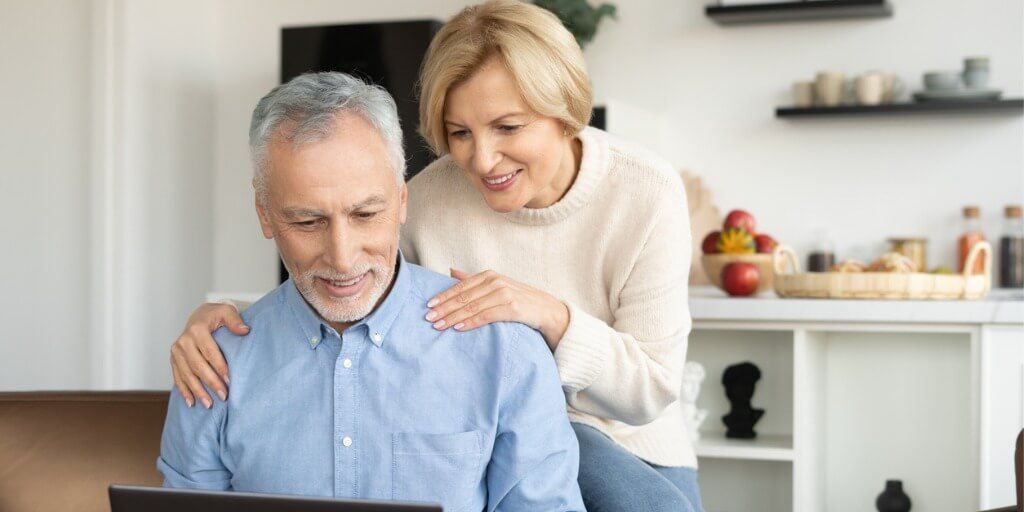 Adult couple looking at health insurance information on a laptop at home