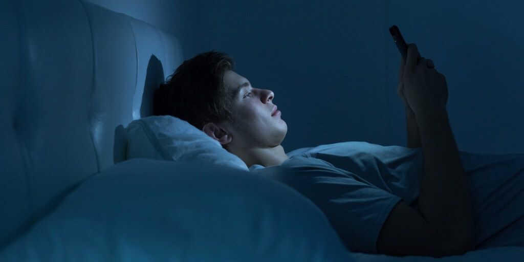 Young man on phone in bed 