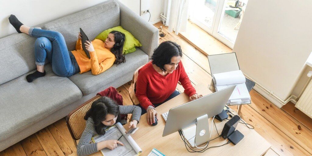 busy mom working on computer with two kids around her
