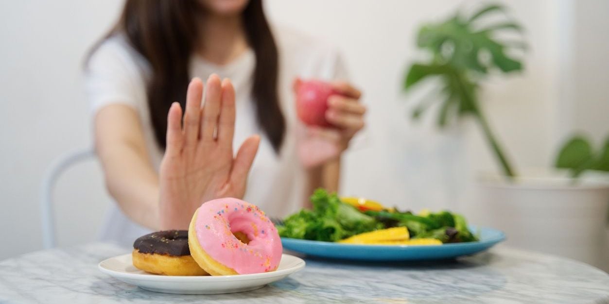 Woman reaching for healthy vs. sugary foods.