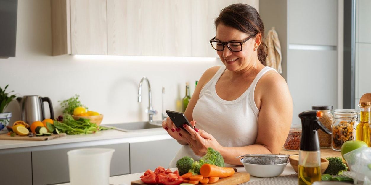 Woman cooking while on her phone