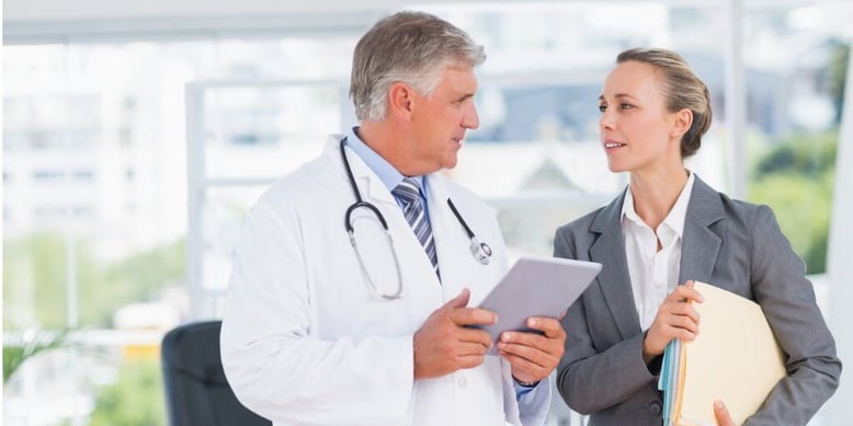 Male physician talking with businesswoman about her executive physical results. 