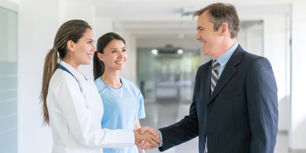 Male executive shaking hands with female doctor during executive physical