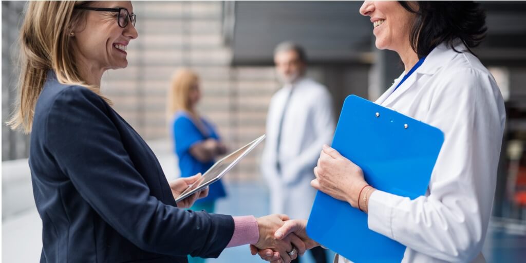 Female executive shaking hands with female doctor after physical