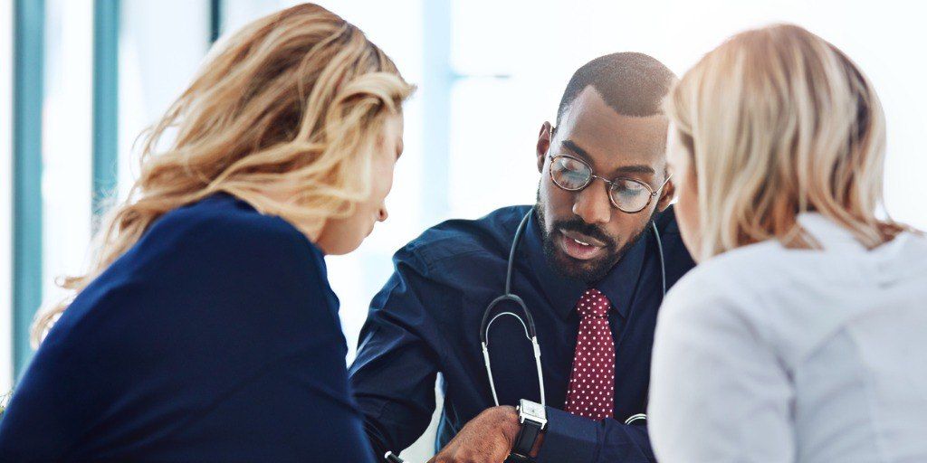 Physician meeting with two employees during executive physical