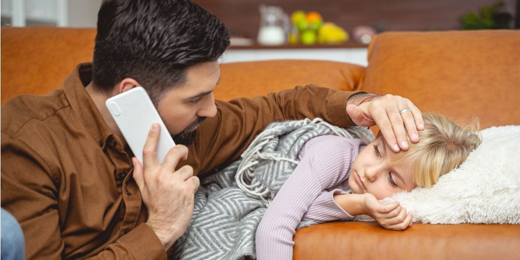 Father feeling his young daughter's forehead. 