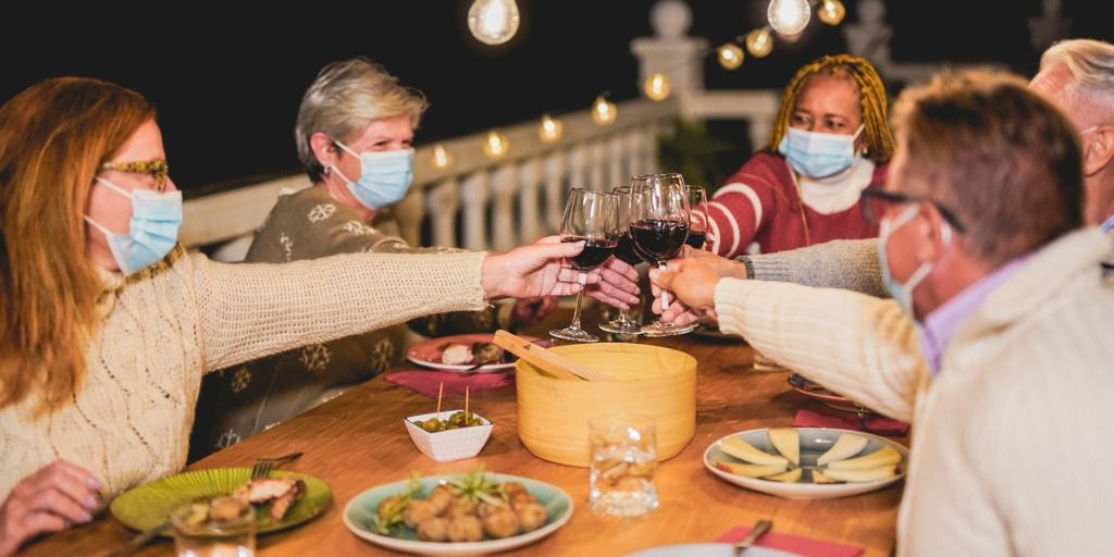 happy-multiracial-senior-people-cheering-with-red-wine-at-dinner-picture-id1280526363