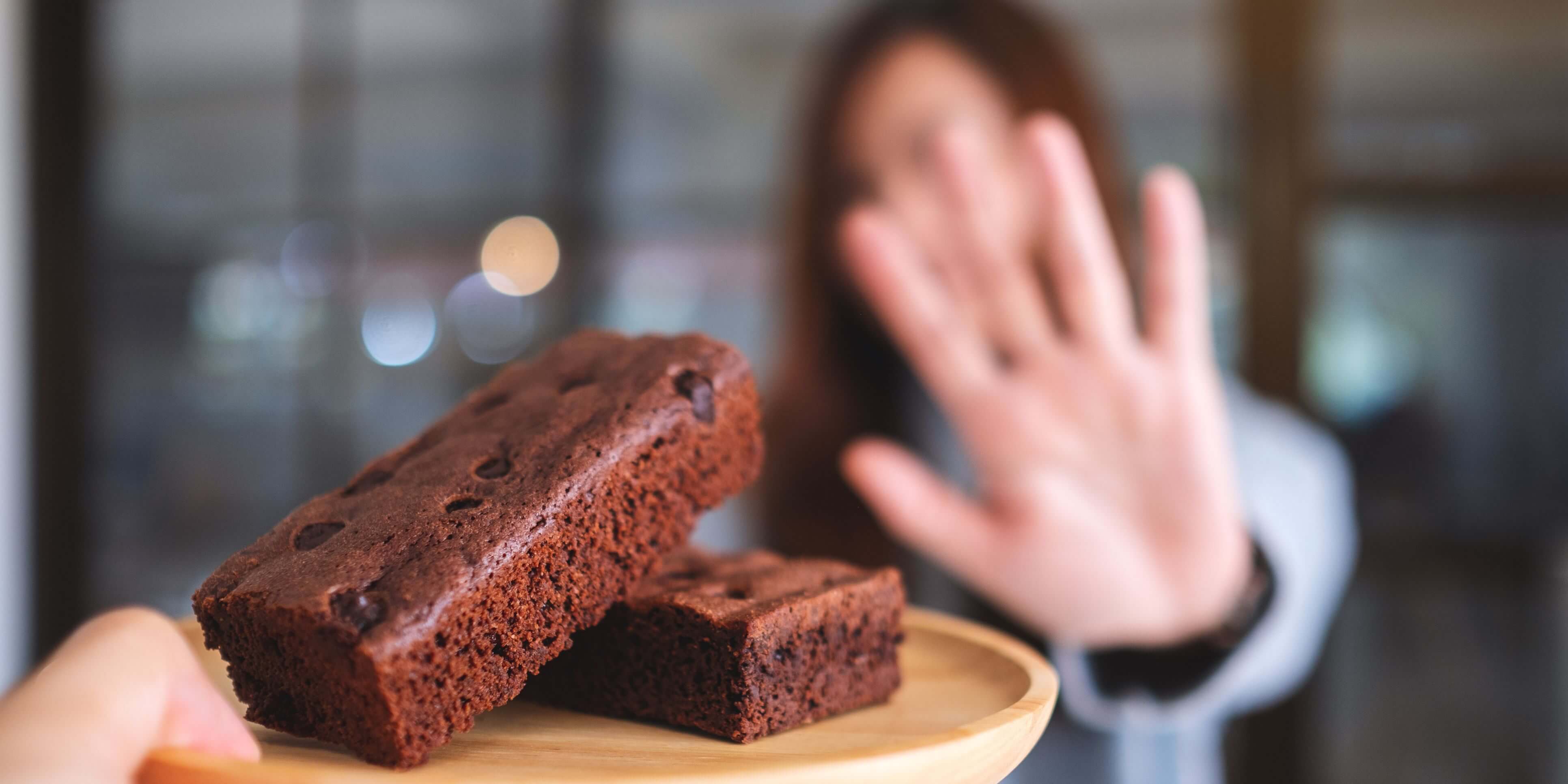 A woman rejecting brownies. 