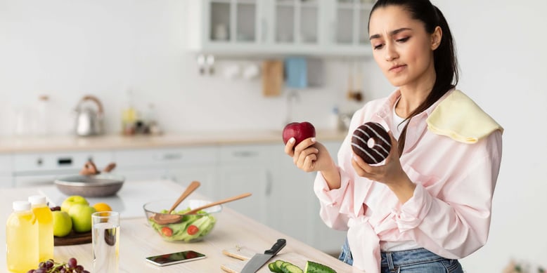 A woman choosing between an apple and donut.