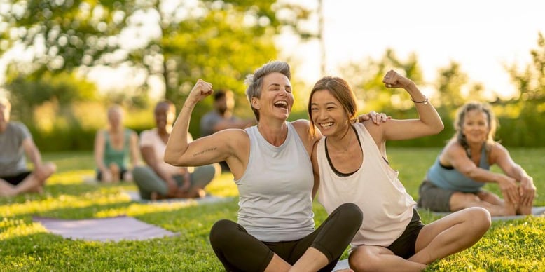 two women smiling while doing yoga
