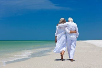 elderly couple walking on the beach