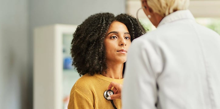 Doctor checking patient's lungs/heart with a stethoscope. 