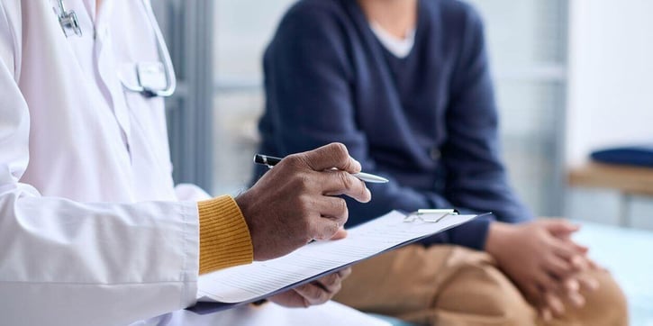 patient talking to doctor who is holding a clipboard