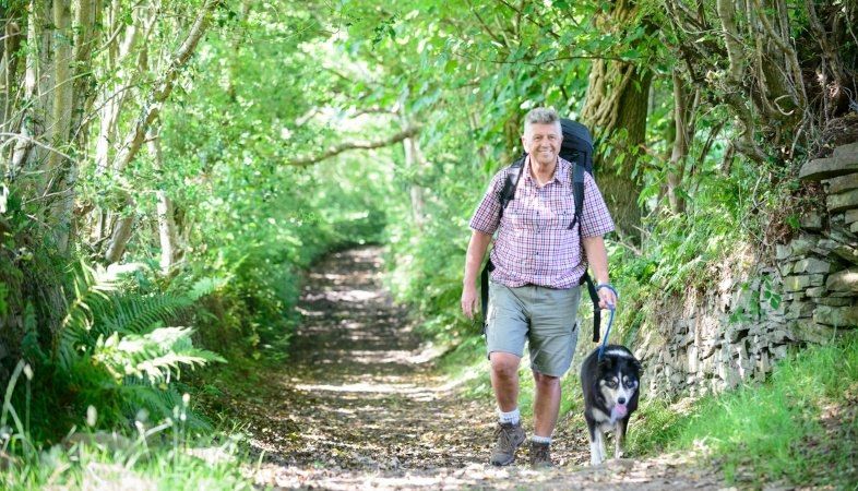 Older man walking in woods with his dog
