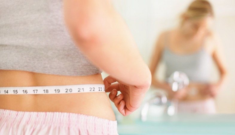 woman measuring her waistline