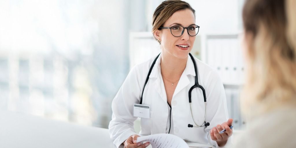 Female doctor talking to a patient at her desk