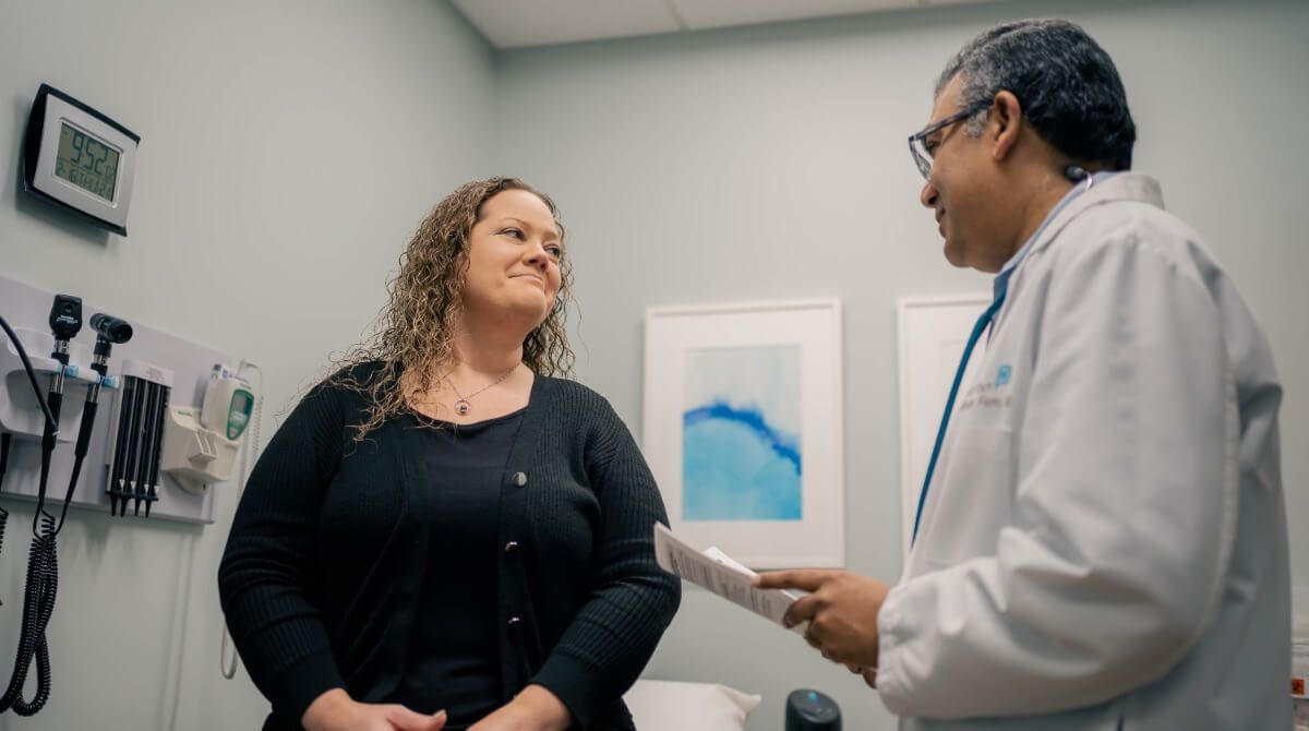 Dr. Sarma, holistic doctor in Sandy Springs, talking with a female patient in an exam room