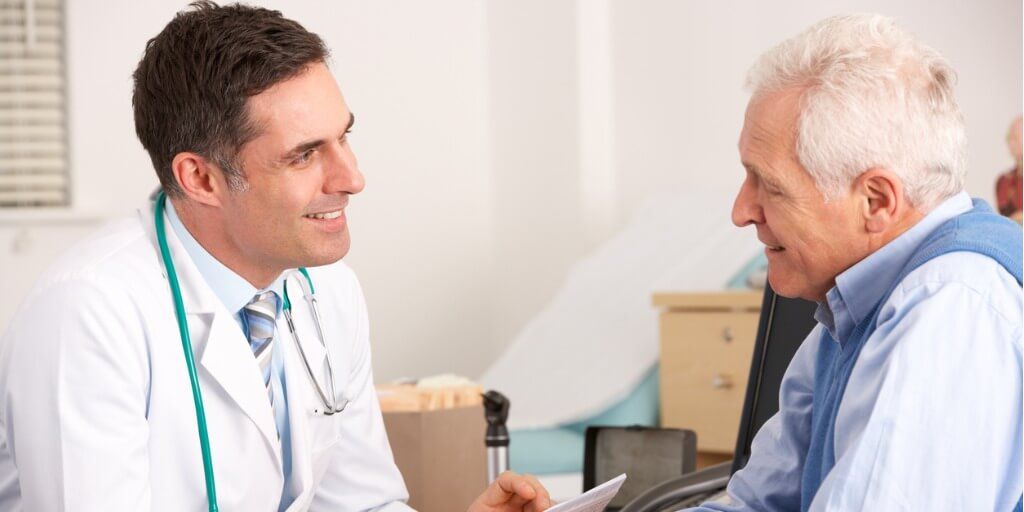 Male physician chatting with older male patient