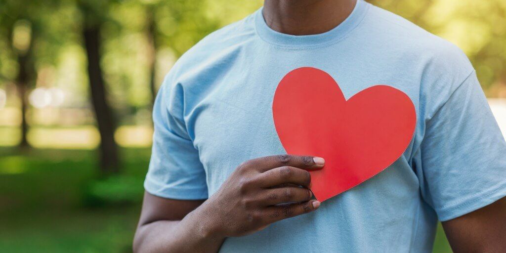 Man holding a paper heart in a park