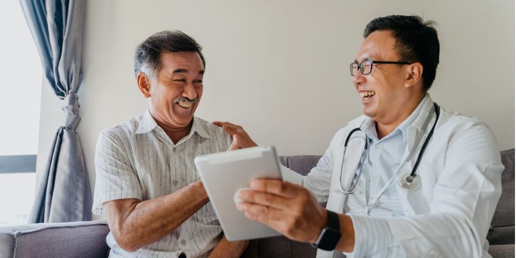 Physician laughing with patient and looking at tablet