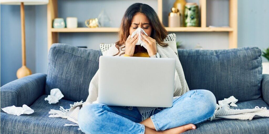 woman sick on couch with tissues next to her