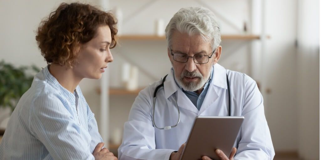 Male physician sitting with female patient