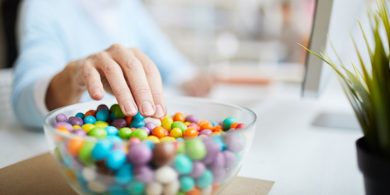 Woman reaching for candy bowl.