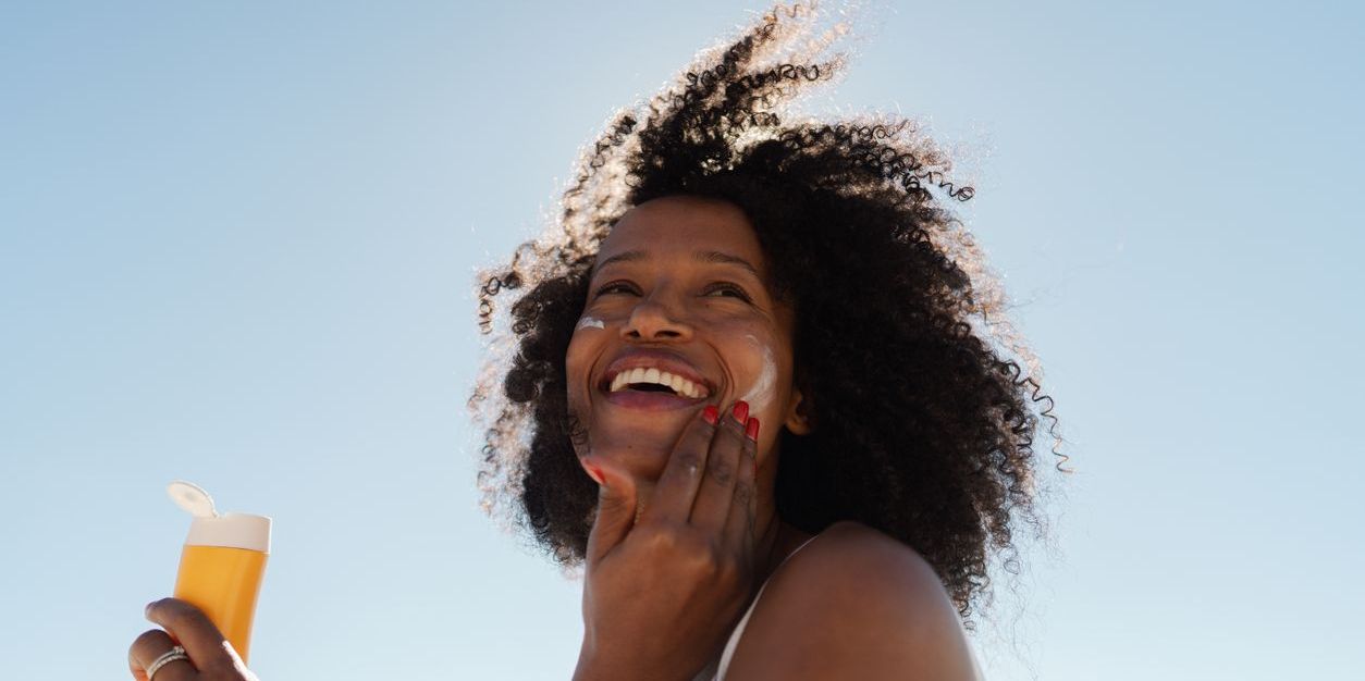 Woman applying sunscreen to her face. 